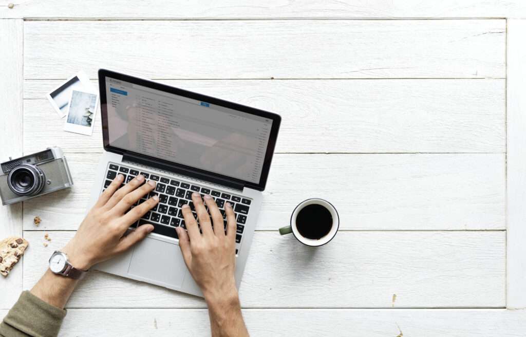 Laptop na drewnianym stole – Praca i hobby Widok z góry na laptopa leżącego na drewnianym stole, z elementami związanymi z pracą lub hobby.